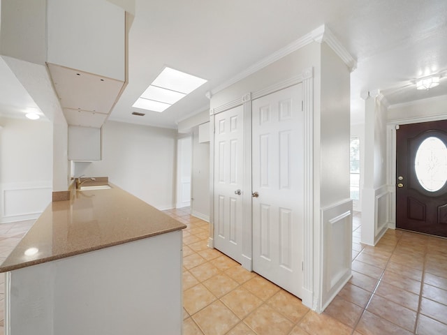 kitchen with ornamental molding, sink, and light tile patterned floors