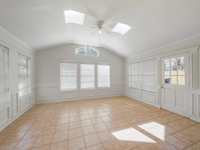 interior space with light tile patterned floors, crown molding, lofted ceiling with skylight, and ceiling fan