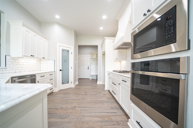 kitchen featuring white cabinetry, stainless steel appliances, light stone counters, and light wood-type flooring