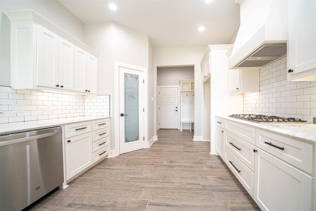 kitchen featuring premium range hood, white cabinetry, light hardwood / wood-style floors, stainless steel appliances, and light stone countertops