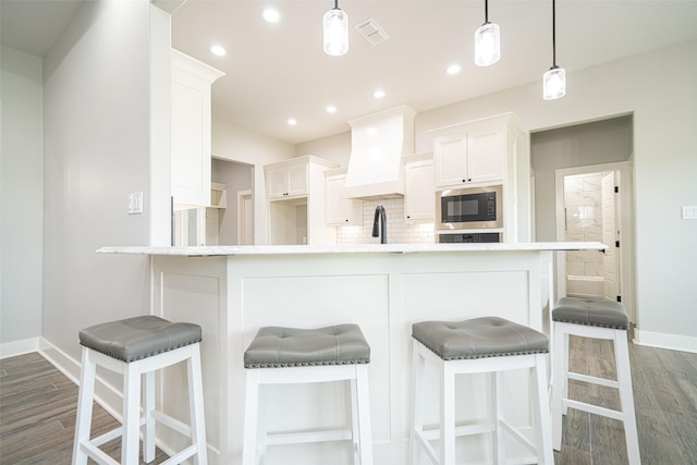 kitchen with white cabinetry, tasteful backsplash, custom exhaust hood, and black microwave