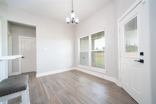 unfurnished dining area featuring wood-type flooring and a notable chandelier