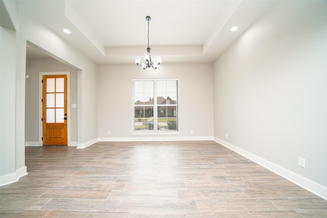 spare room featuring a raised ceiling and an inviting chandelier