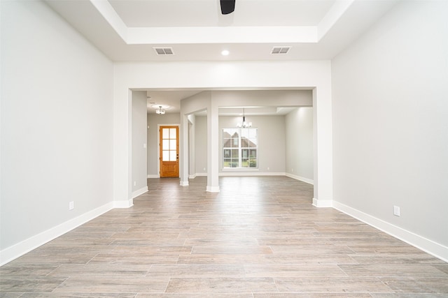 empty room with a tray ceiling and ceiling fan with notable chandelier