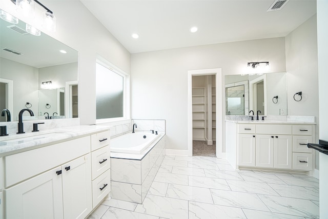 bathroom featuring a relaxing tiled tub and vanity