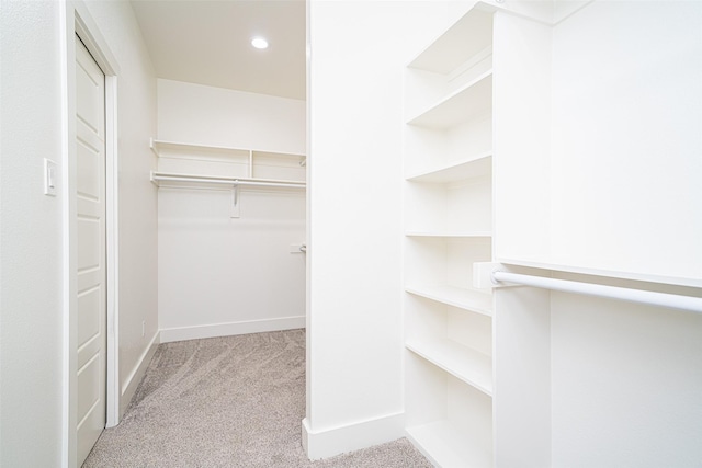 walk in closet featuring light colored carpet