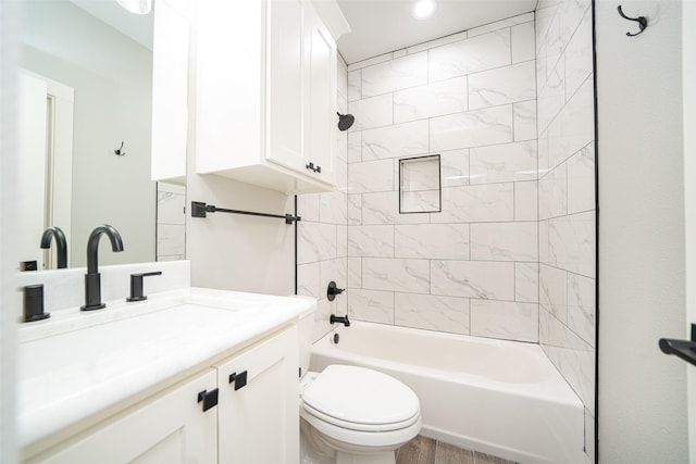 full bathroom featuring hardwood / wood-style flooring, tiled shower / bath, vanity, and toilet