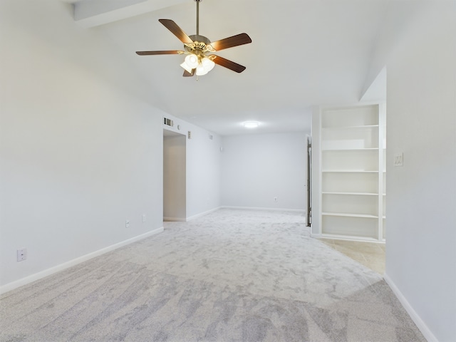 unfurnished room with vaulted ceiling with beams, built in shelves, light colored carpet, and ceiling fan