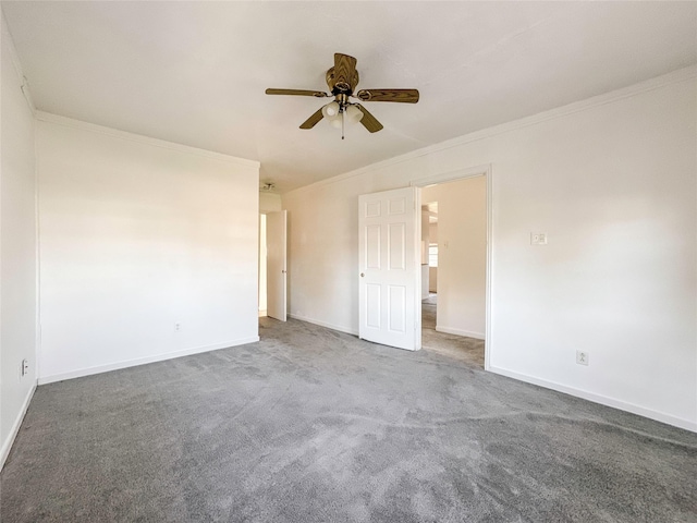 empty room with ornamental molding, ceiling fan, and dark carpet