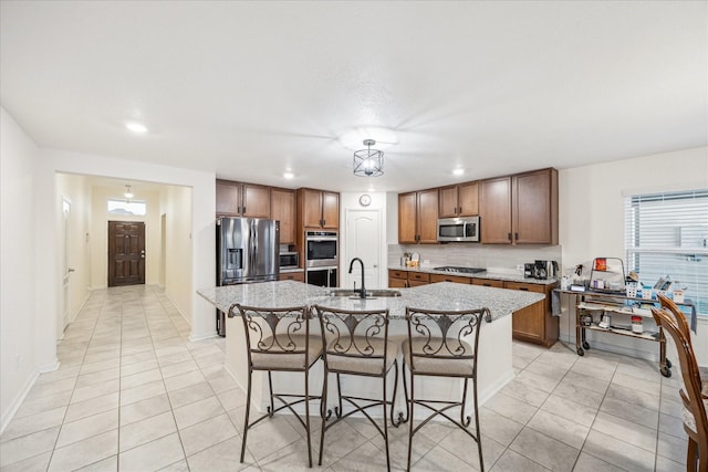 kitchen featuring appliances with stainless steel finishes, tasteful backsplash, sink, a kitchen breakfast bar, and a kitchen island with sink