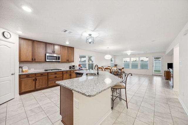 kitchen featuring sink, a breakfast bar area, a kitchen island with sink, backsplash, and stainless steel appliances