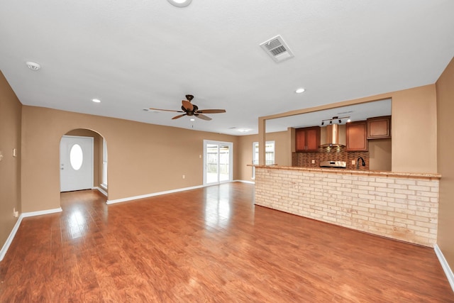 unfurnished living room with sink, wood-type flooring, and ceiling fan