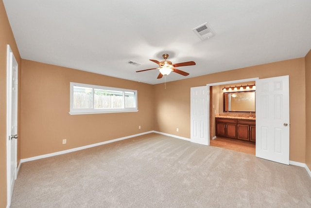 unfurnished bedroom with light carpet, ceiling fan, and ensuite bathroom