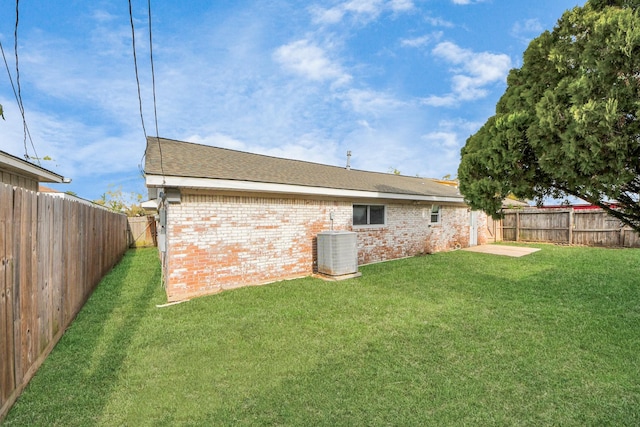 back of property with a yard and central AC