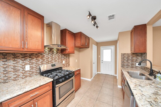 kitchen with light stone counters, sink, wall chimney exhaust hood, and appliances with stainless steel finishes