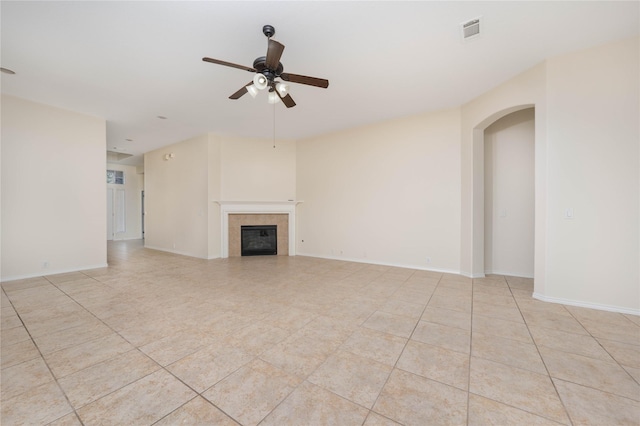 unfurnished living room featuring ceiling fan, a tiled fireplace, and light tile patterned floors