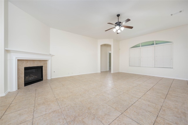 unfurnished living room featuring ceiling fan, light tile patterned flooring, and a fireplace