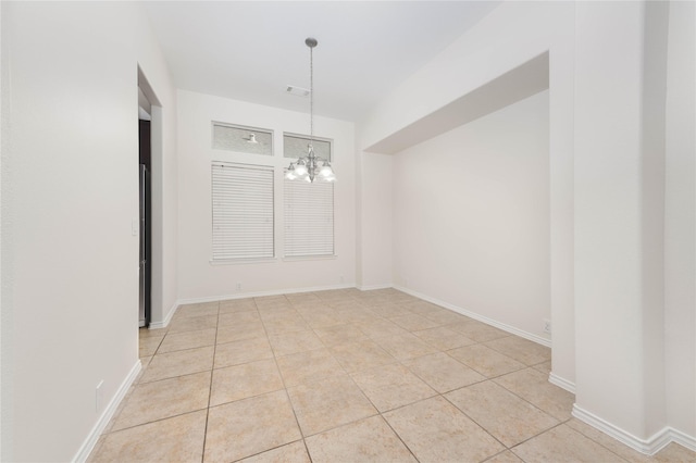 empty room with light tile patterned floors and an inviting chandelier