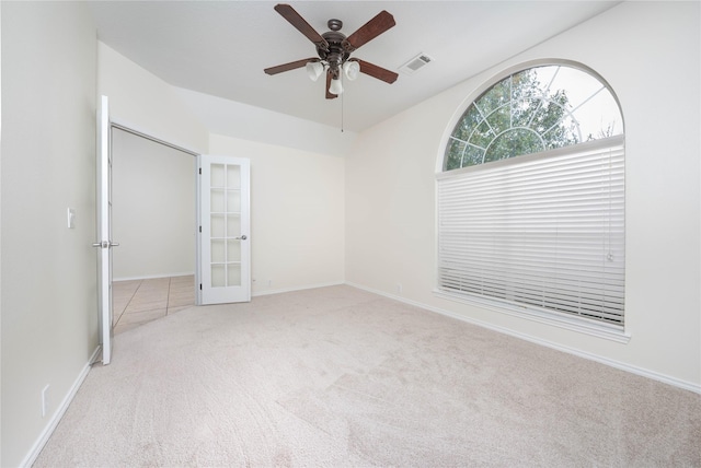 empty room featuring vaulted ceiling, light colored carpet, french doors, and ceiling fan