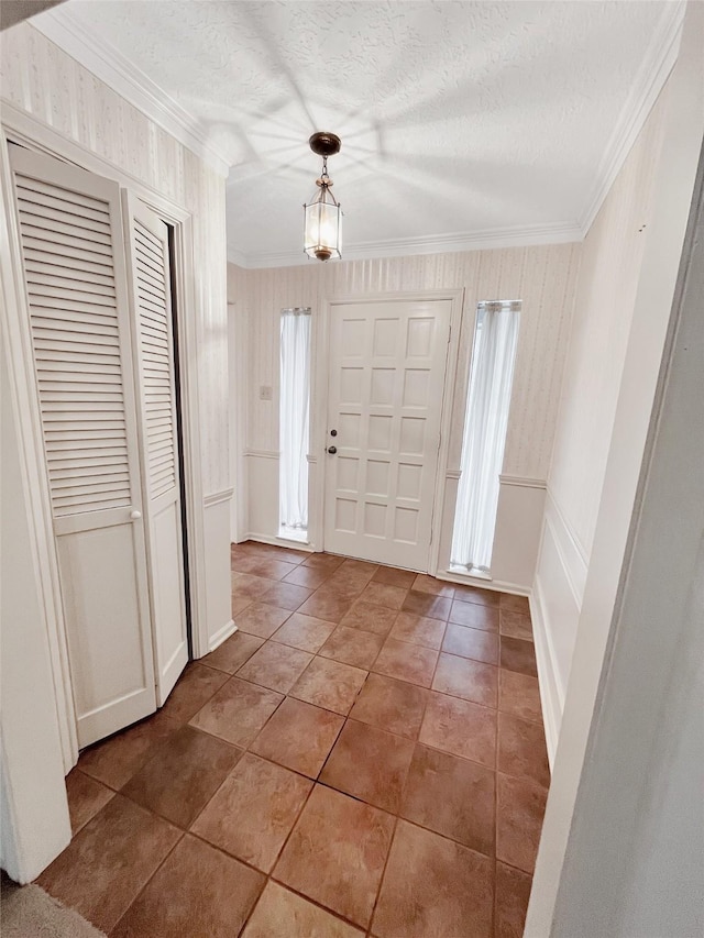 tiled foyer featuring crown molding and a textured ceiling