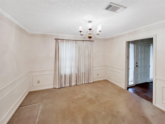 carpeted empty room featuring crown molding, a textured ceiling, and a chandelier