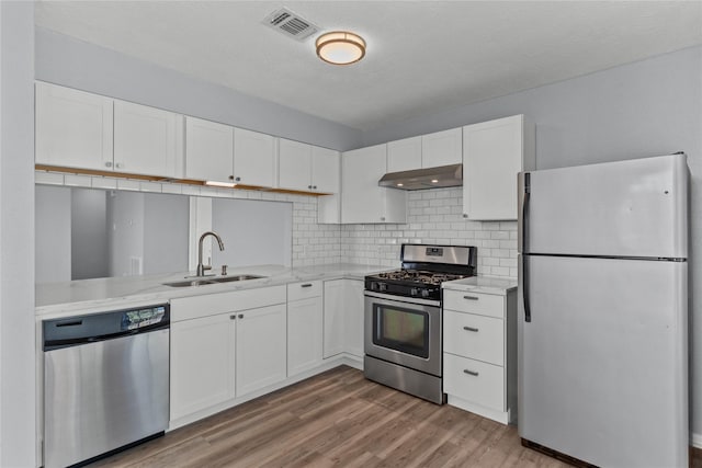 kitchen featuring sink, white cabinetry, tasteful backsplash, light hardwood / wood-style flooring, and appliances with stainless steel finishes