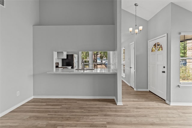 kitchen with decorative light fixtures, sink, a notable chandelier, kitchen peninsula, and stainless steel appliances