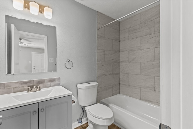 full bathroom with ceiling fan, tiled shower / bath combo, tasteful backsplash, vanity, and toilet