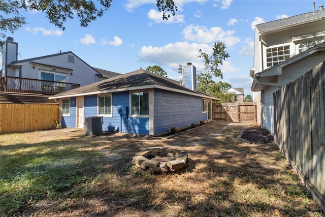 rear view of property featuring cooling unit, a yard, and an outdoor fire pit