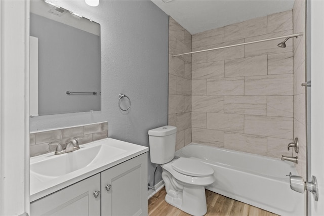 full bathroom with vanity, toilet, tiled shower / bath combo, and hardwood / wood-style floors