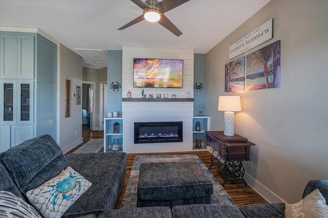 living room with ceiling fan, a large fireplace, and dark hardwood / wood-style floors