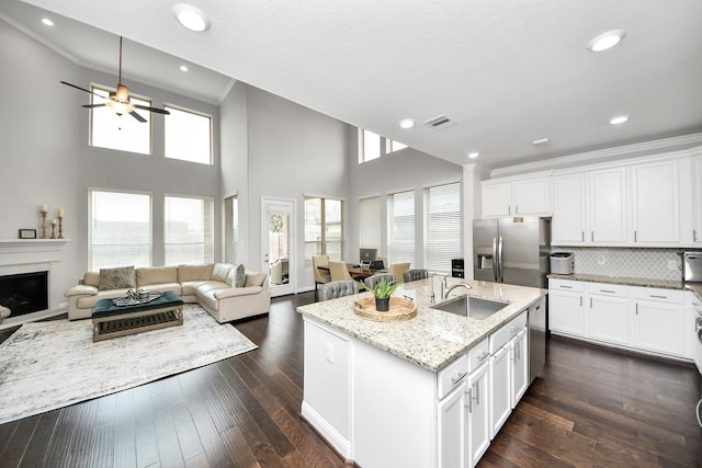 kitchen featuring stainless steel appliances, an island with sink, white cabinets, and light stone counters