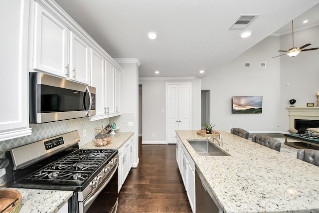 kitchen with sink, white cabinetry, a center island with sink, stainless steel appliances, and light stone countertops