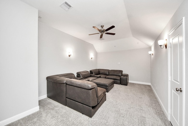 carpeted home theater room with ceiling fan and a tray ceiling