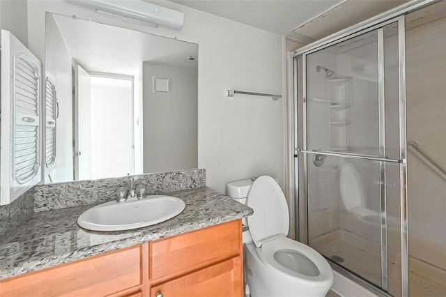 bathroom featuring vanity, a shower with door, and toilet