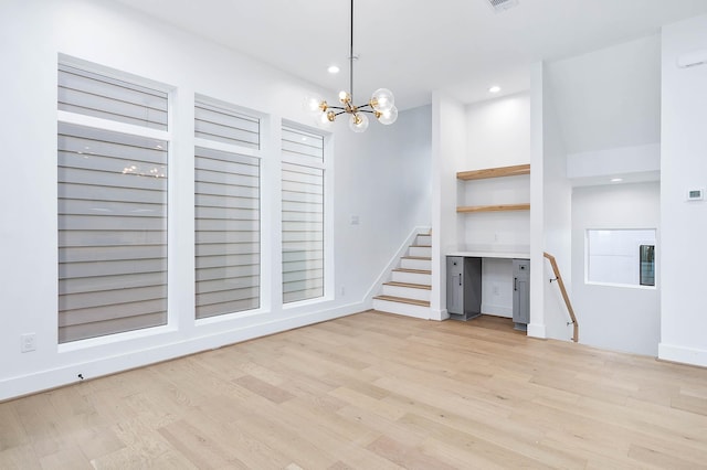 unfurnished living room with a chandelier and light wood-type flooring