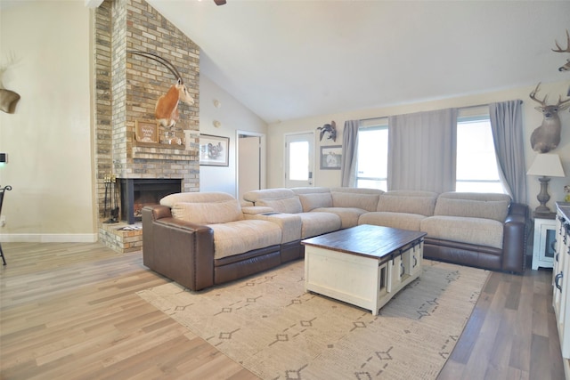 living room with a fireplace, light hardwood / wood-style flooring, high vaulted ceiling, and plenty of natural light