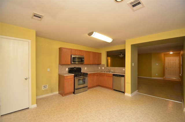 kitchen with appliances with stainless steel finishes, sink, and decorative backsplash