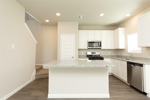 kitchen featuring stainless steel appliances, white cabinetry, a kitchen island, and sink