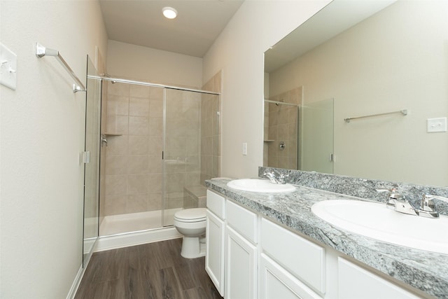 bathroom with wood-type flooring, toilet, a shower with shower door, and vanity