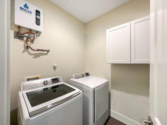 clothes washing area with cabinets, washing machine and dryer, dark hardwood / wood-style floors, and tankless water heater