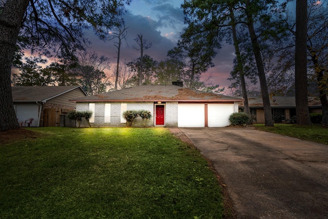 single story home featuring a garage, driveway, a chimney, a front yard, and brick siding