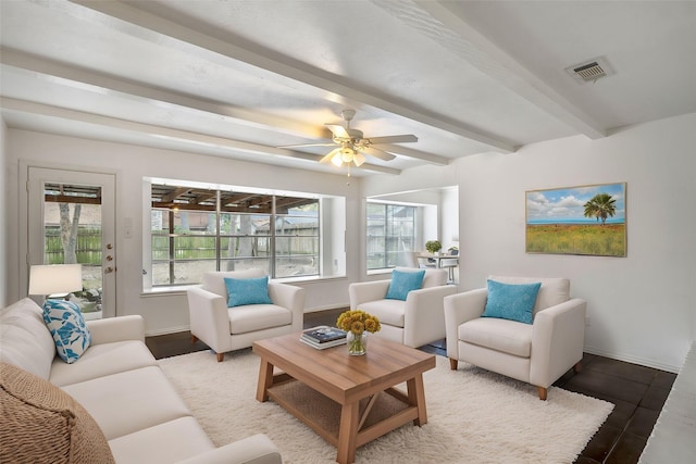 living area featuring a ceiling fan, baseboards, visible vents, and beam ceiling