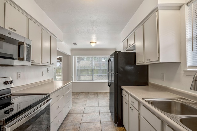 kitchen with stainless steel appliances, sink, and light tile patterned floors