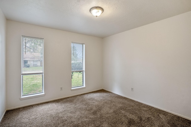 carpeted empty room with a textured ceiling and baseboards