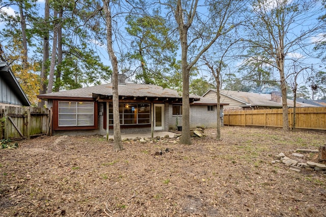 back of property featuring a fenced backyard, a chimney, and brick siding