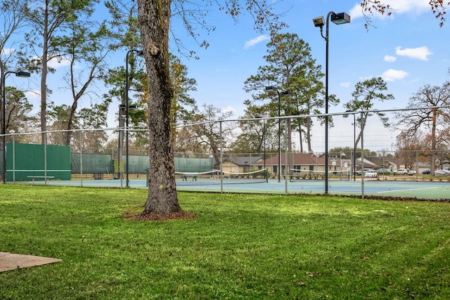 view of tennis court featuring a yard