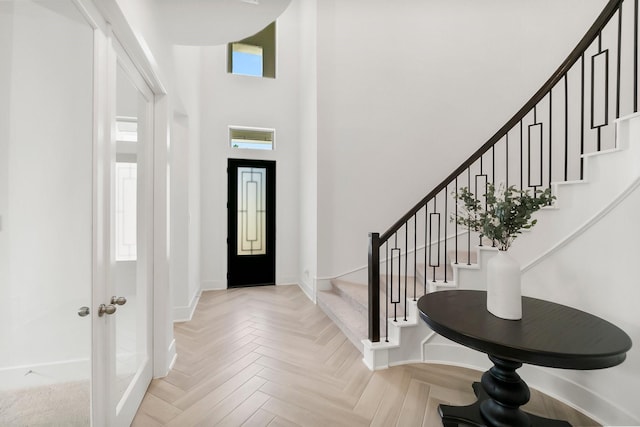 entryway featuring a towering ceiling and light parquet floors