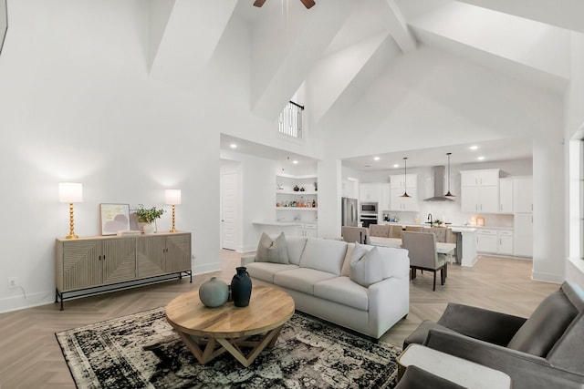 living room with a high ceiling, light parquet floors, ceiling fan, and built in shelves