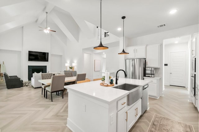 kitchen featuring pendant lighting, sink, appliances with stainless steel finishes, a kitchen island with sink, and white cabinets